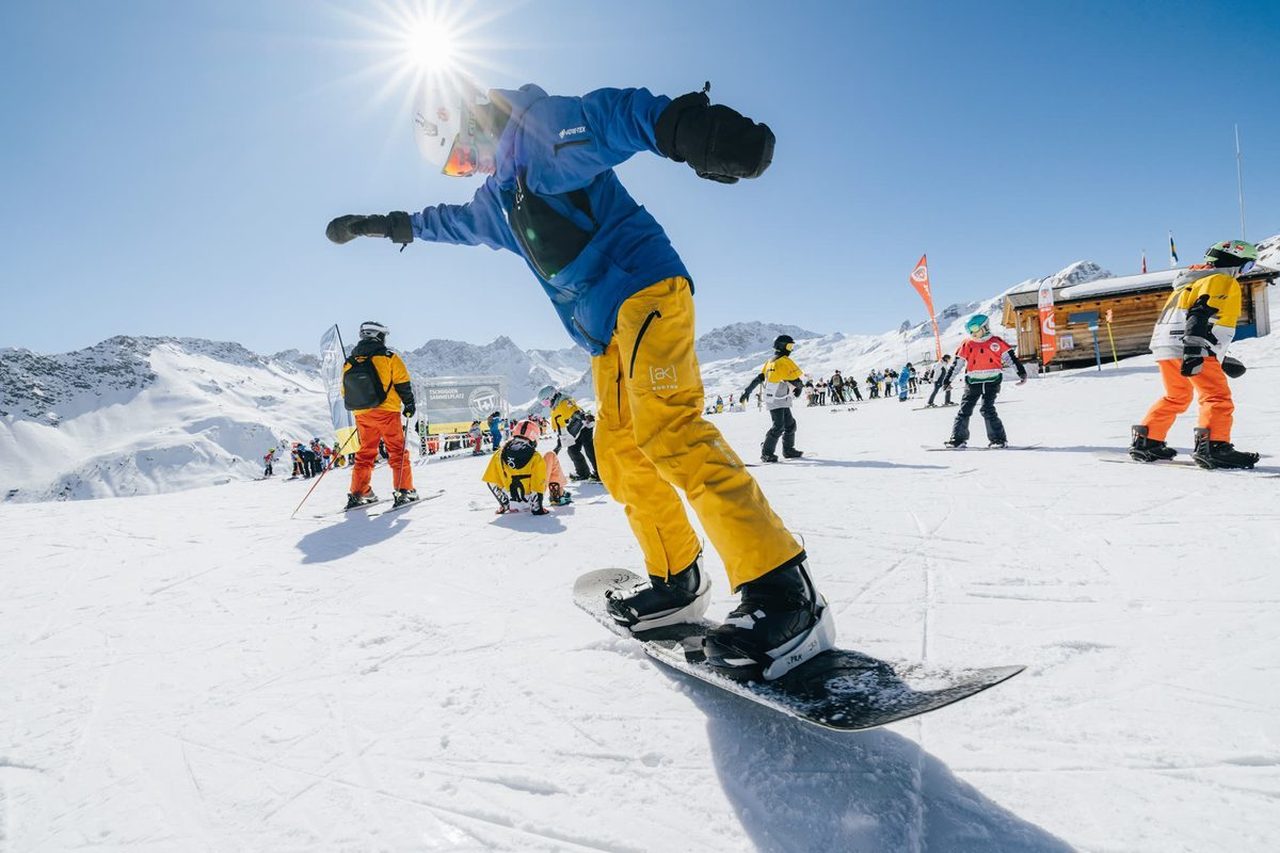 Snowboardlehrer der Skischule Arosa fährt einer Gruppe auf der Piste voraus